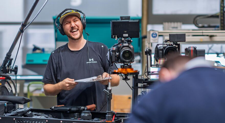 Florian Klaes lacht während eines Videodrehs, umringt von seinem Videoequipment
