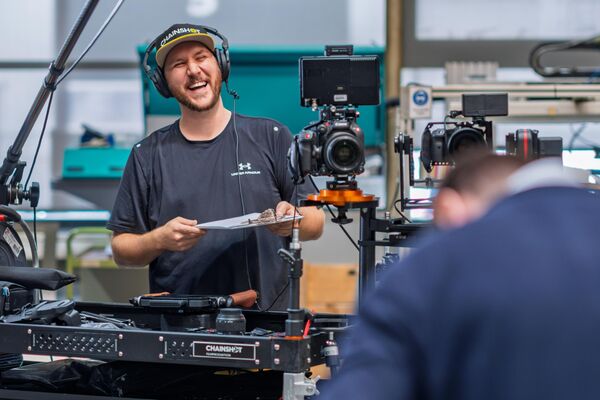 Florian Klaes lacht während eines Videodrehs, umringt von seinem Videoequipment